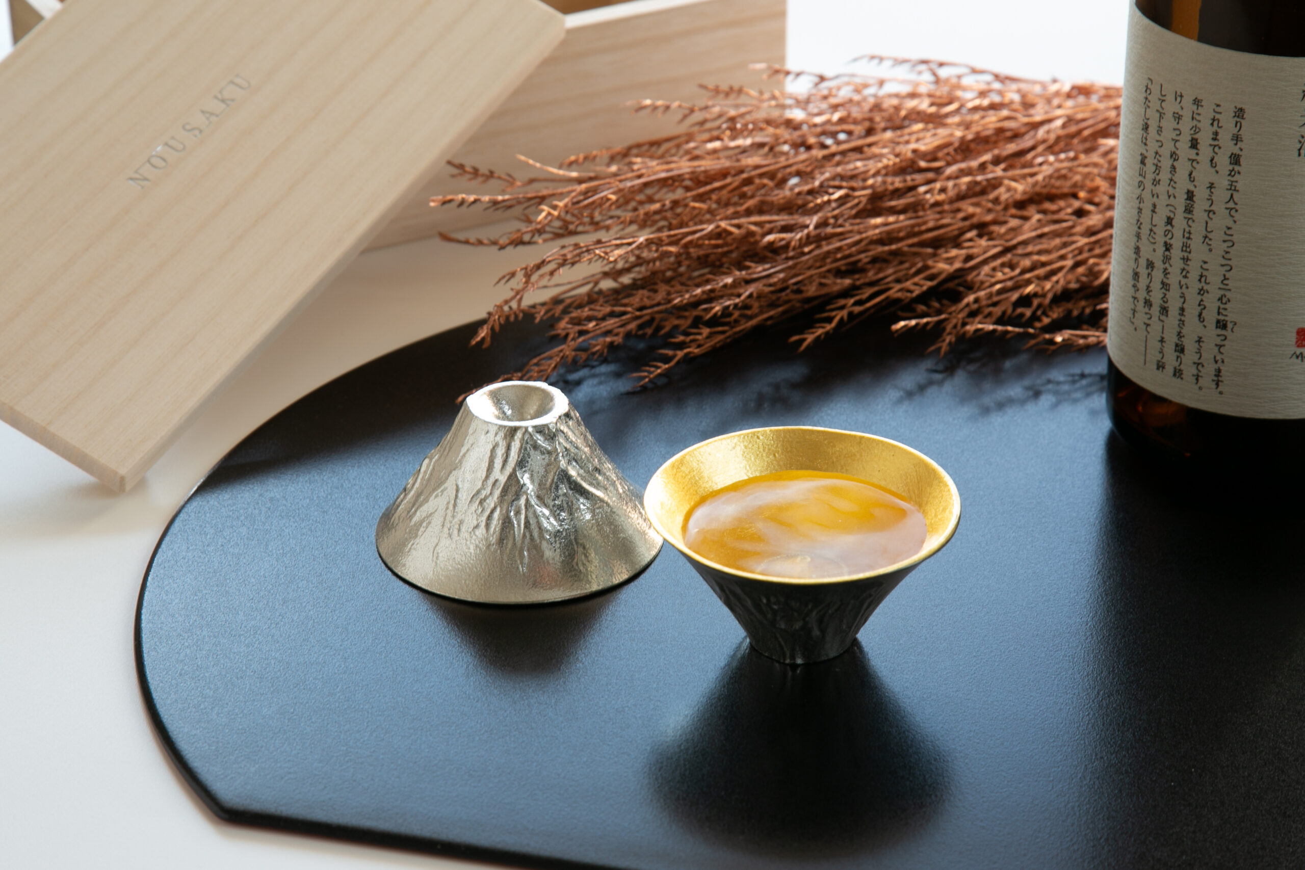 Nousaku Mt. Fuji sake cup with gold interior beside sake bottle